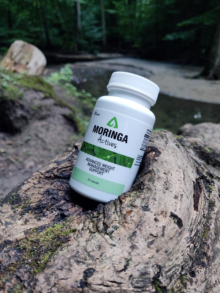 envase blanca y verde con letras negras sobre una piedra en la naturaleza.