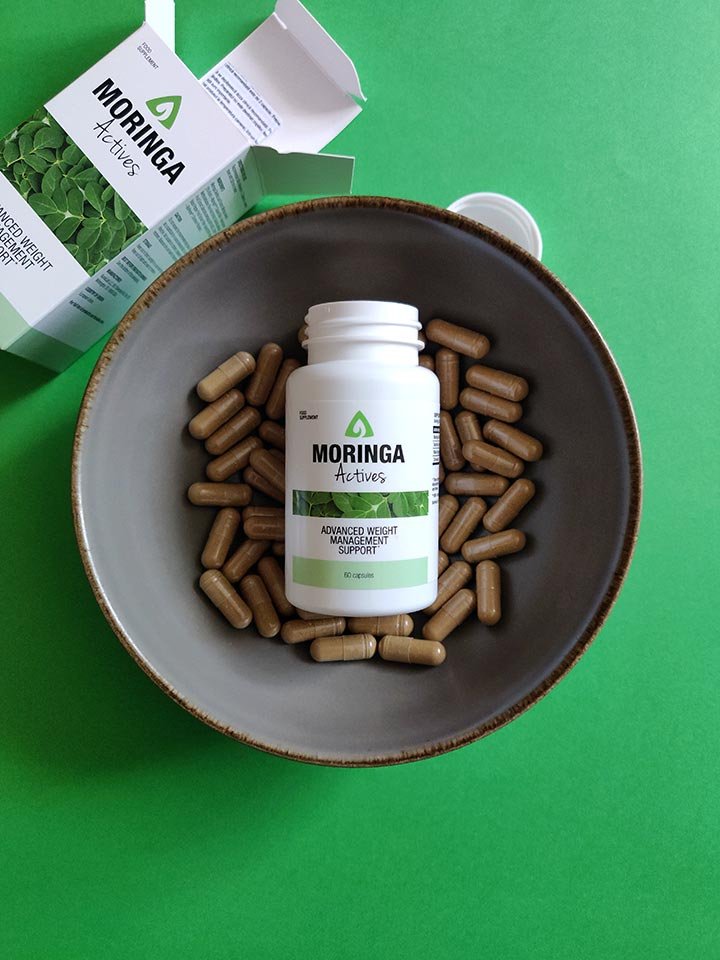 caja con envase blanca y verde con letras negras dentro de cuenco con capsulas de suplemento