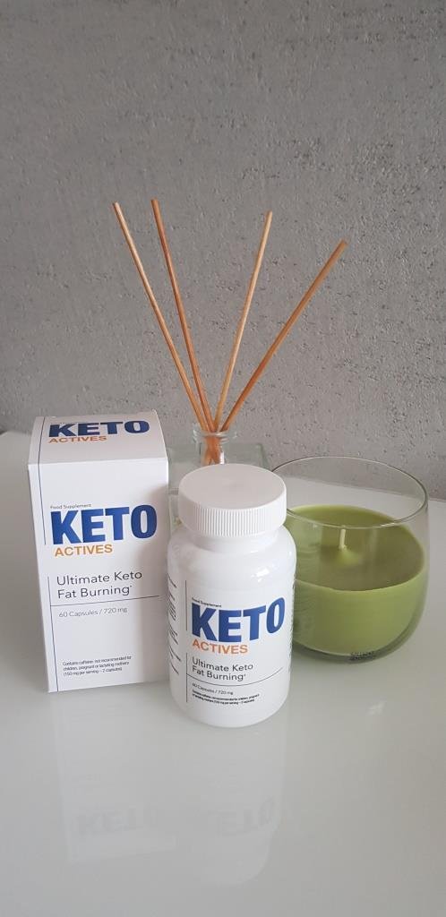 envase y caja de color blanco  con letras azules junto a vela aromática y palos de ambientador.