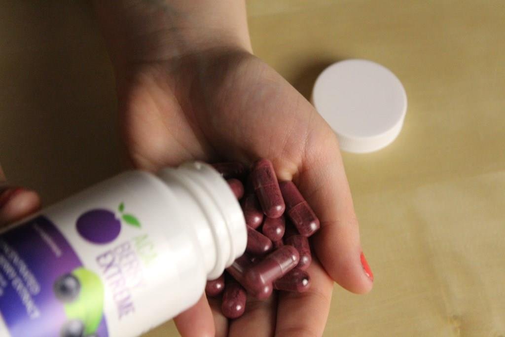 envase de suplemento y capsulas en una mano.