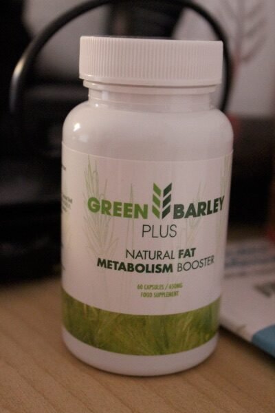 envase de green barley plus sobre fondo blanco y naturaleza verde con letras verdes sobre una mesa.