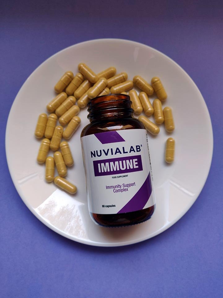 Bote de suplemento volcado en un plato + capsulas