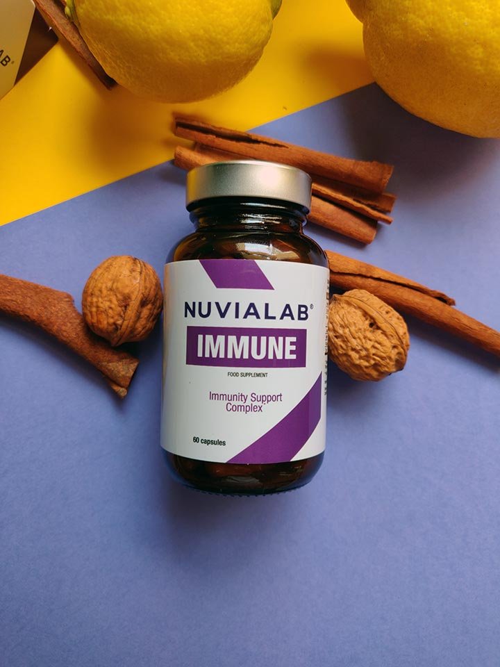 Bote de suplemento junto ramas de canela y nueces