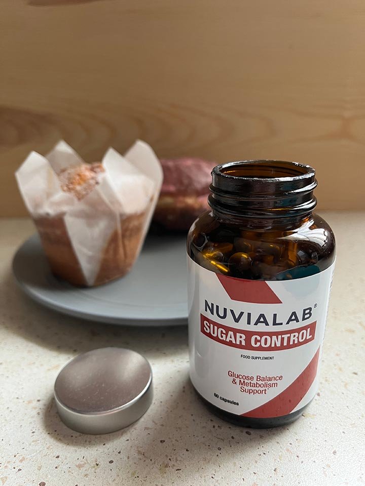 bote de suplemento encima de mesa junto a plato con cup cake